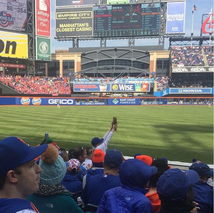 Mets fan holds up glove in stands