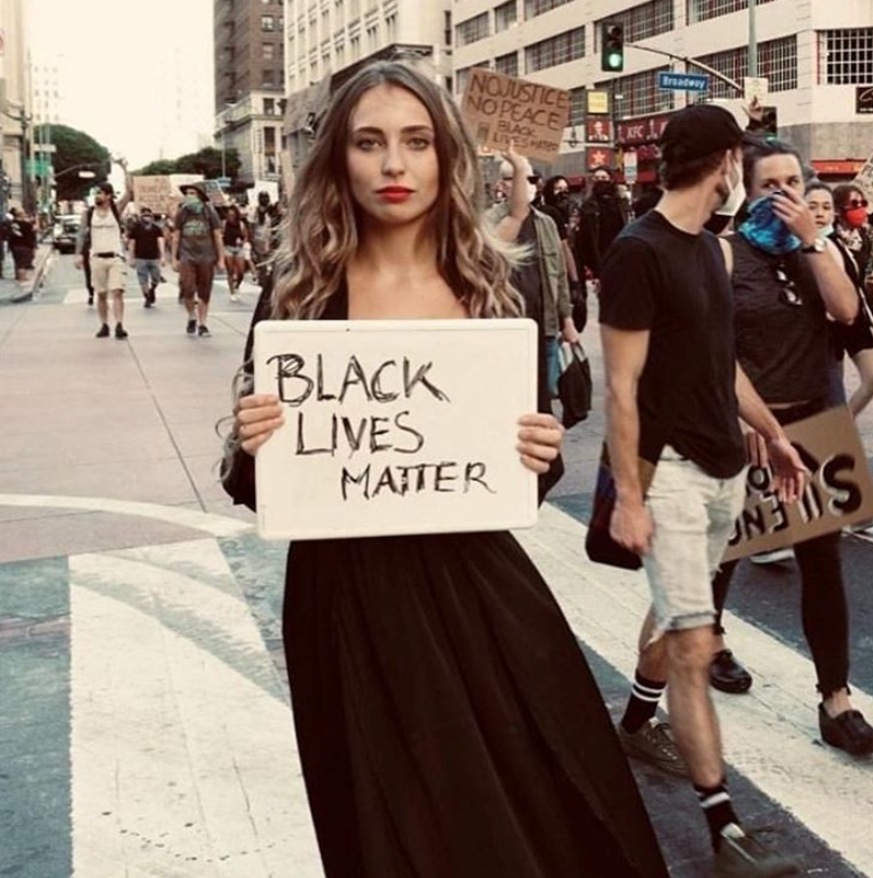 A white influencer holds a Black Lives Matter sign