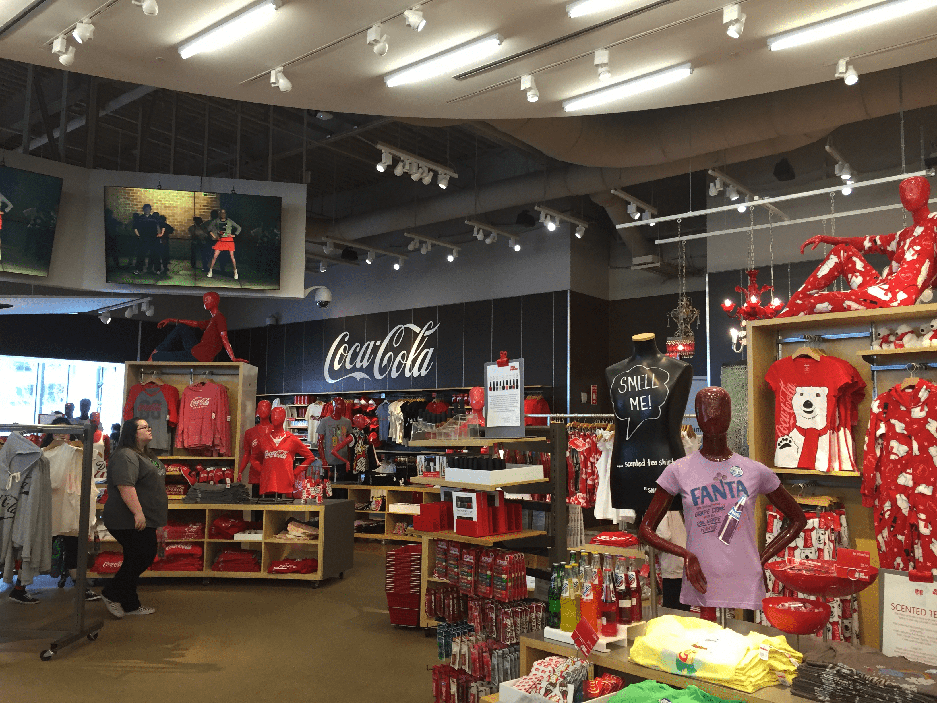 An image from the Coca-Cola store including merchandising like sweatshirts, t-shirts, pajamas, bottles of soda, and chapstick.