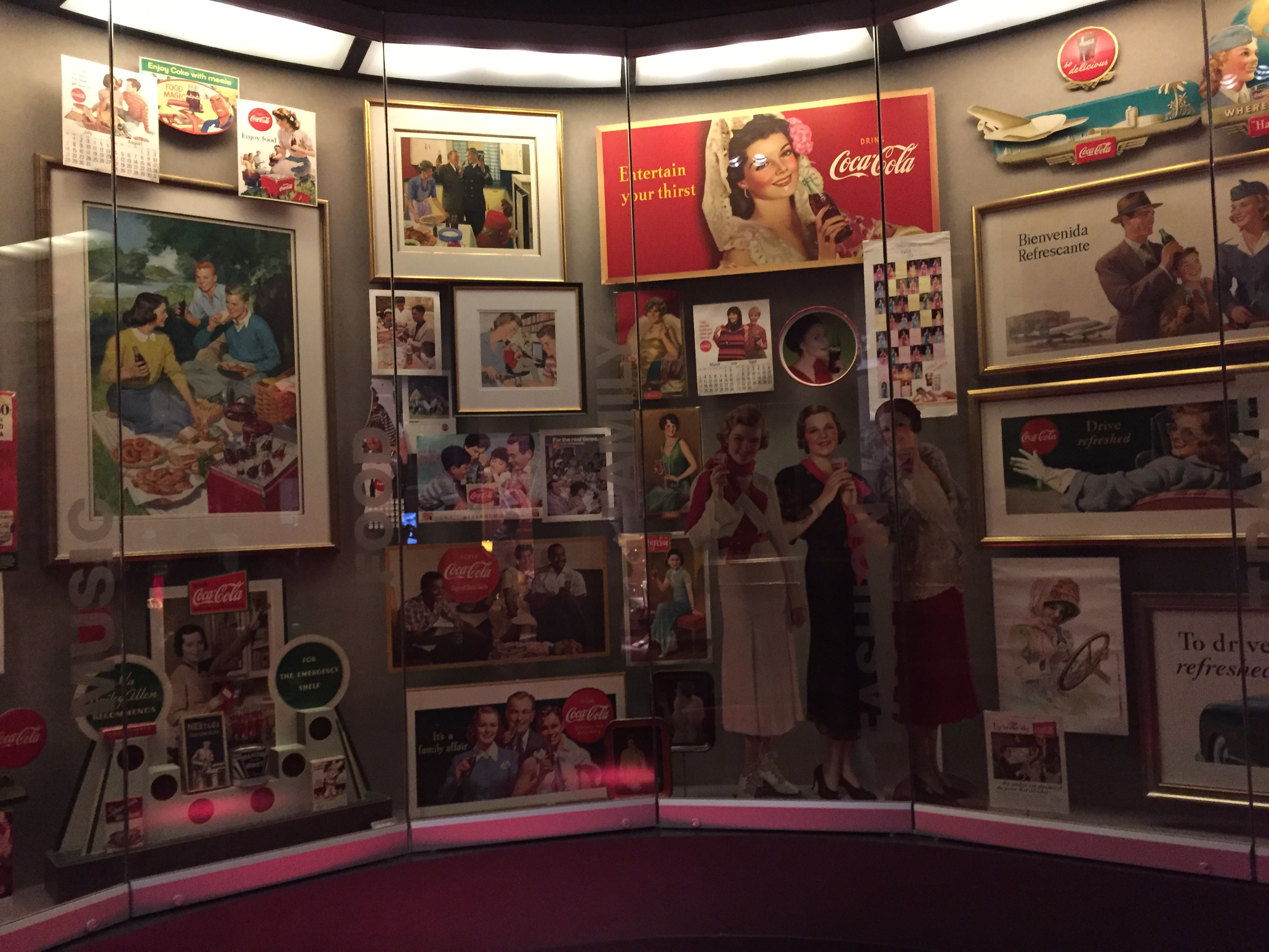 Old Coca-Cola ads and memorabilia on display behind a glass case.