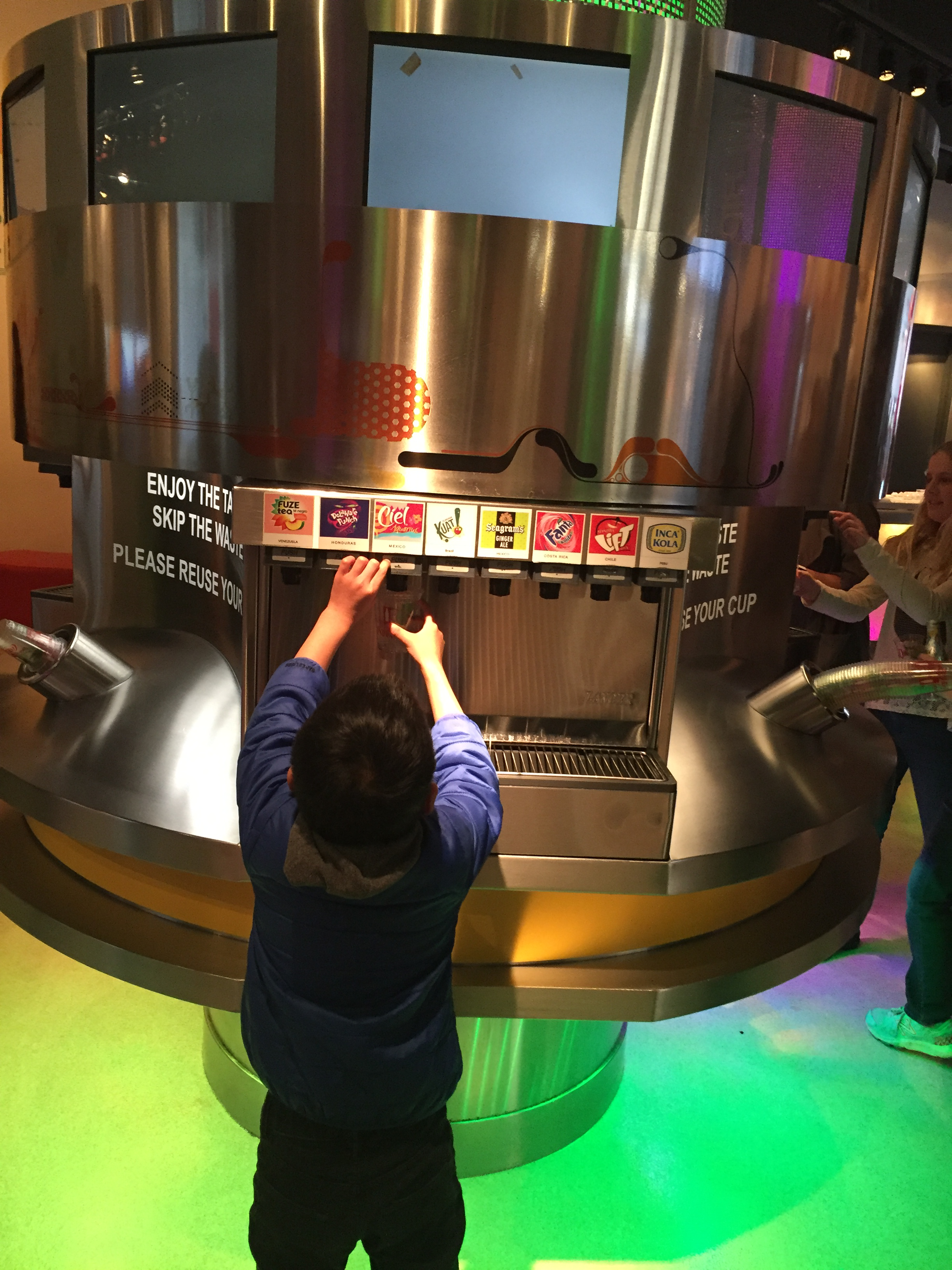 A boy reaches up to dispense a beverage called 