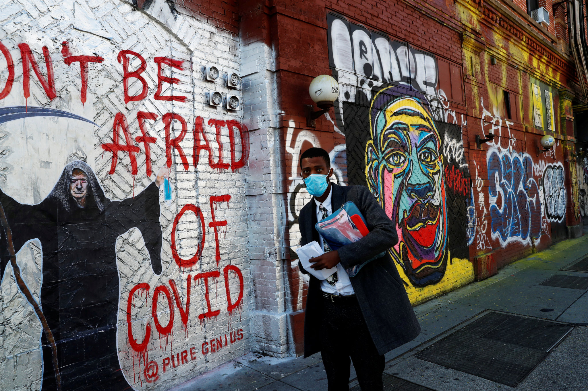 A Man walks past a Covid-19 Mural on Houston Street in NYC