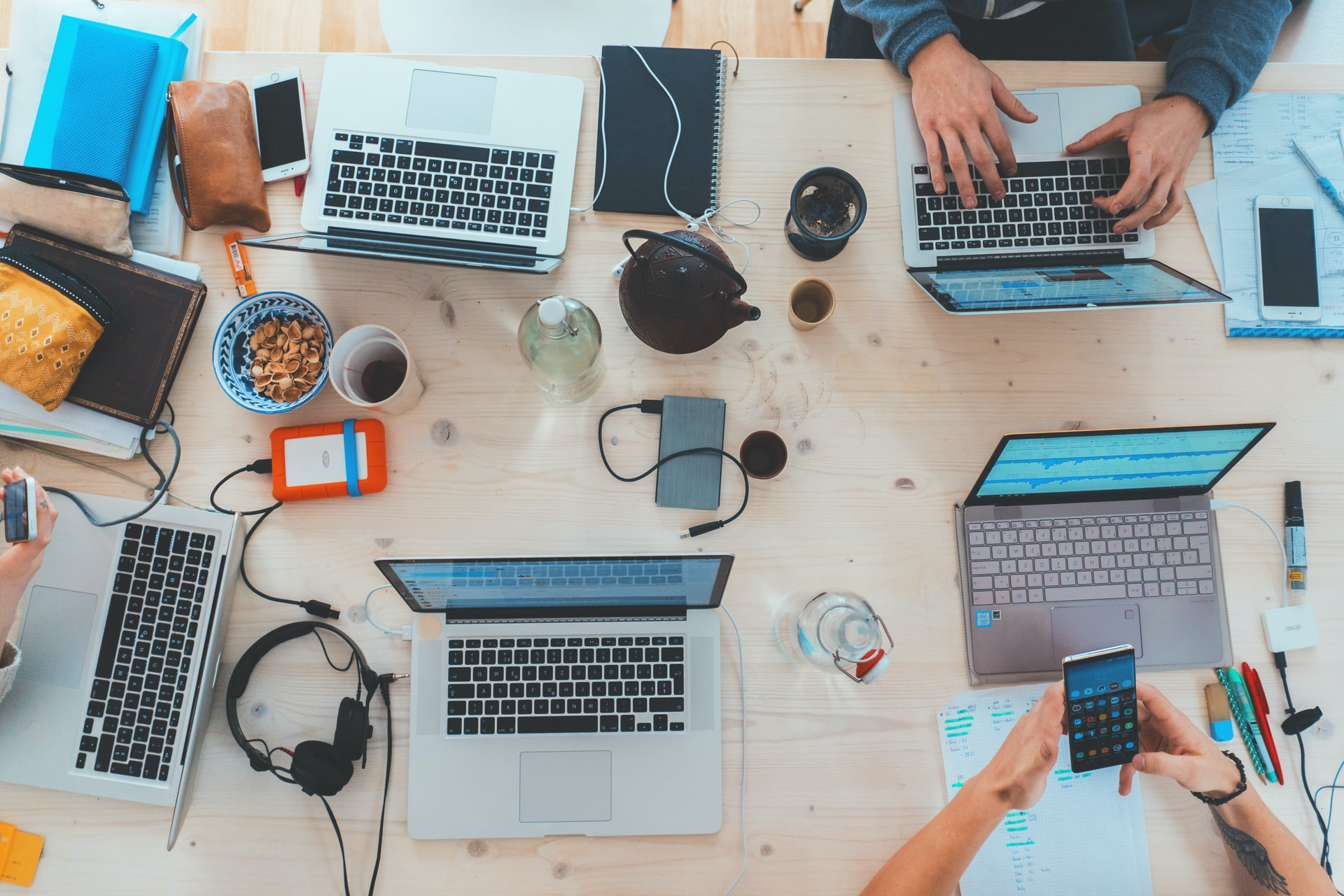 Overhead shot of students studying at a large table with tech devices strewn about