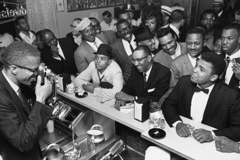 Malcolm X takes a photograph of Cassius Clay on February 25, 1964