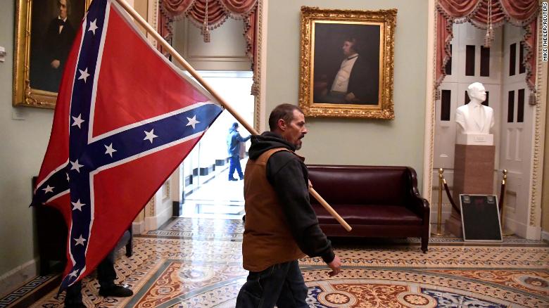 One of the insurrectionists at the U.S. Capitol on 1/6/2021 walks through the second floor of Capitol Hill carrying a Confederate flag