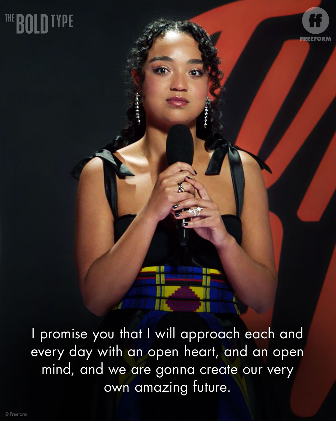 Kat Edison stands on a stage with a microphone. Text reads: I promise you that I will approach each and every day with an open heart, and an open mind, and we are gonna create our very own amazing future.
