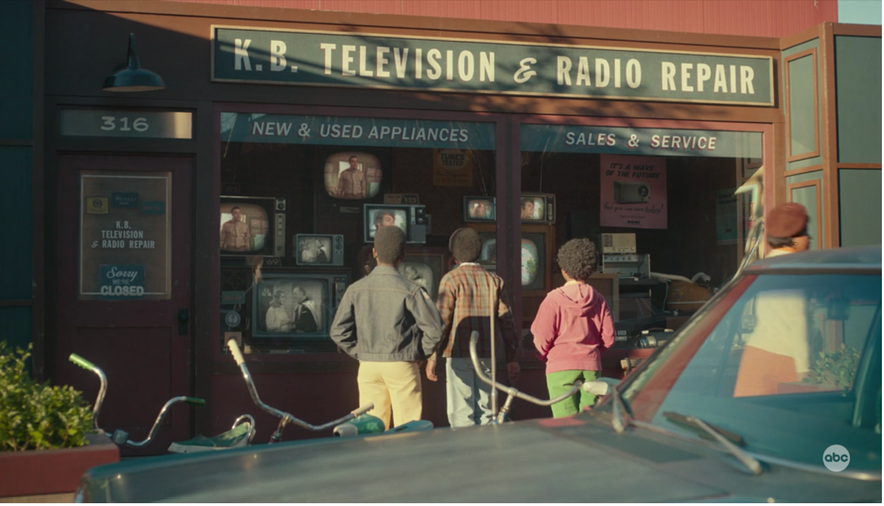 Dean explains television programs to his cousins from the country while looking at a window display of TV sets