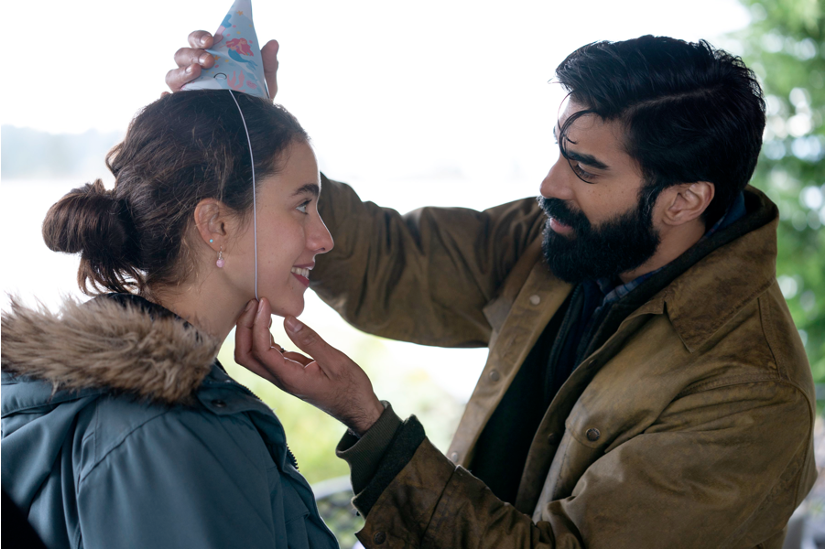 A man with dark hair puts a child's part hat on a young woman with brown hair