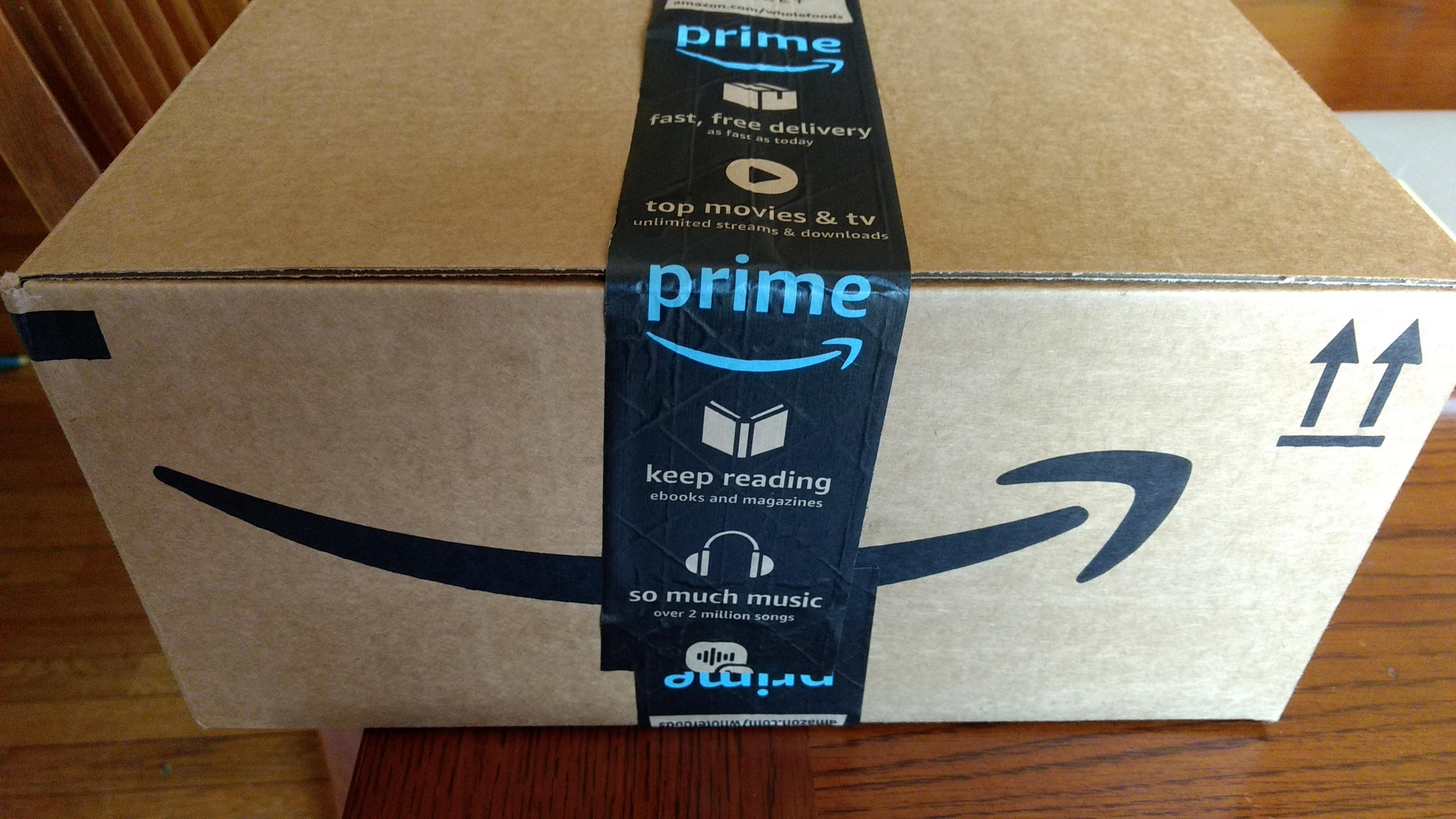 Box covered with Amazon Prime packaging tape advertising diverse offers and services