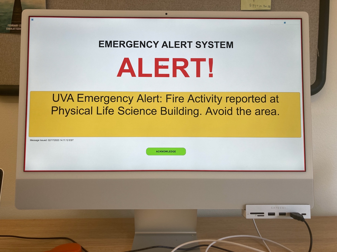 A 'desktop override' emergency alert on the author’s computer screen in a campus office, reading 'EMERGENCY ALERT SYSTEM: ALERT! UVA Emergency Alert: Fire Activity reported at Physical Life Science Building. Avoid the area.'