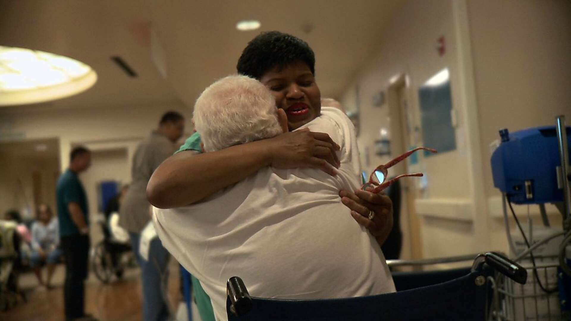 Certified Nurse Assistant Cynthia Y. Johnson embraces a patient in The Waiting Room (2012)
