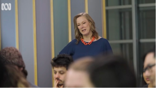 Leigh Sales speaks while standing behind a group of people