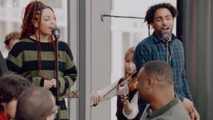 A man and a woman stand at microphones singing