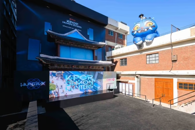 Plaza with entrance to K-pop Demon Hunters store, overlooked by blow-up figures of Derpy and Sussie